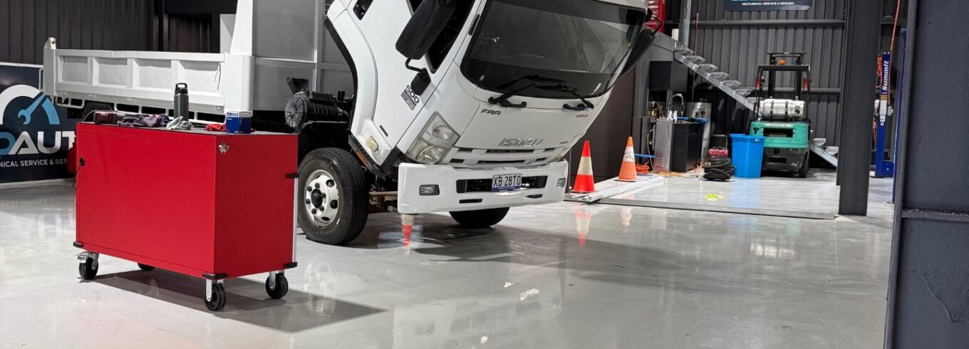 Mechanic inspecting the brakes on a commercial truck in a Brisbane workshop